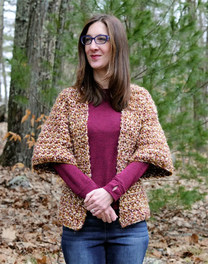 Woman wearing crochet cardigan looking off to the side.
