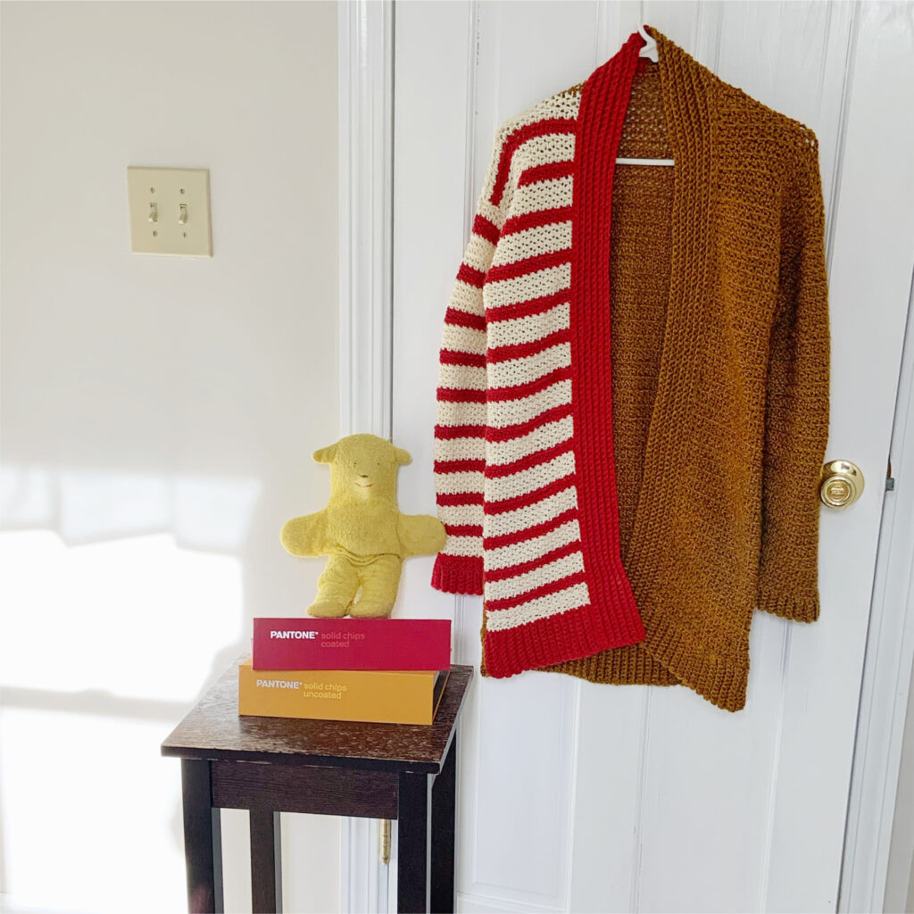 Stripe Blocked Crochet Cardigan hanging on a hook in the sunlight.