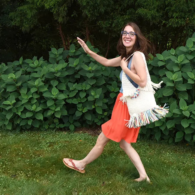 Woman skipping wearing the Super Sunny Tote made from the crochet pattern.