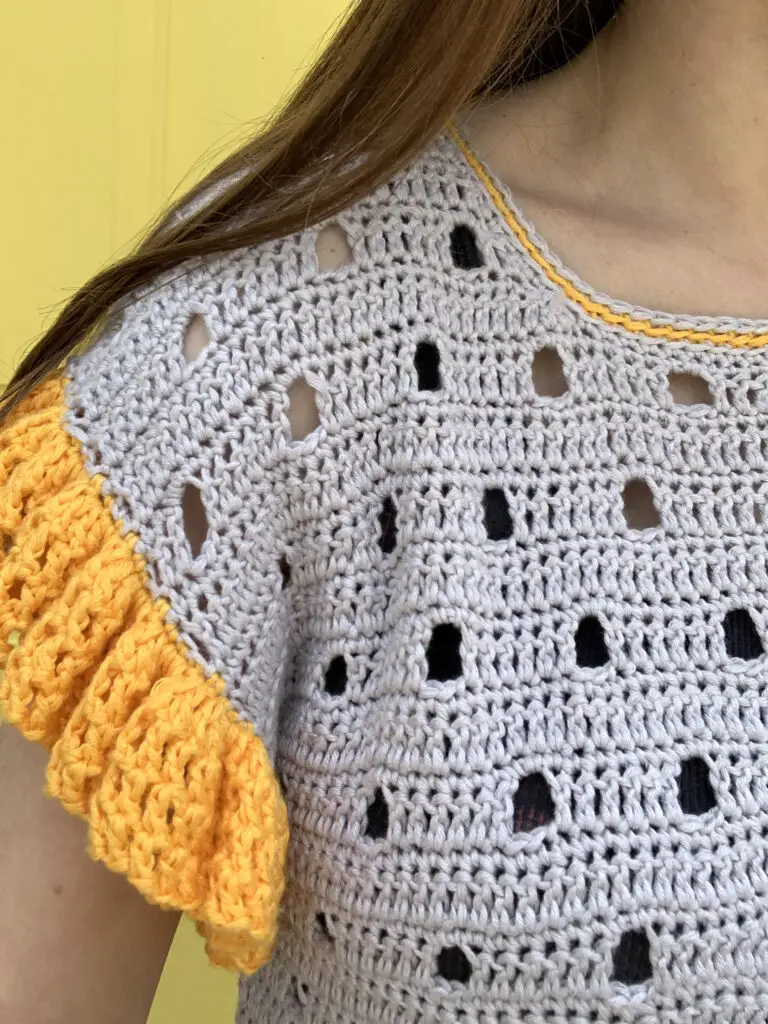 The delicate collar detail, ruffled sleeves, and unique stitch make this crochet tee a truly unique design.