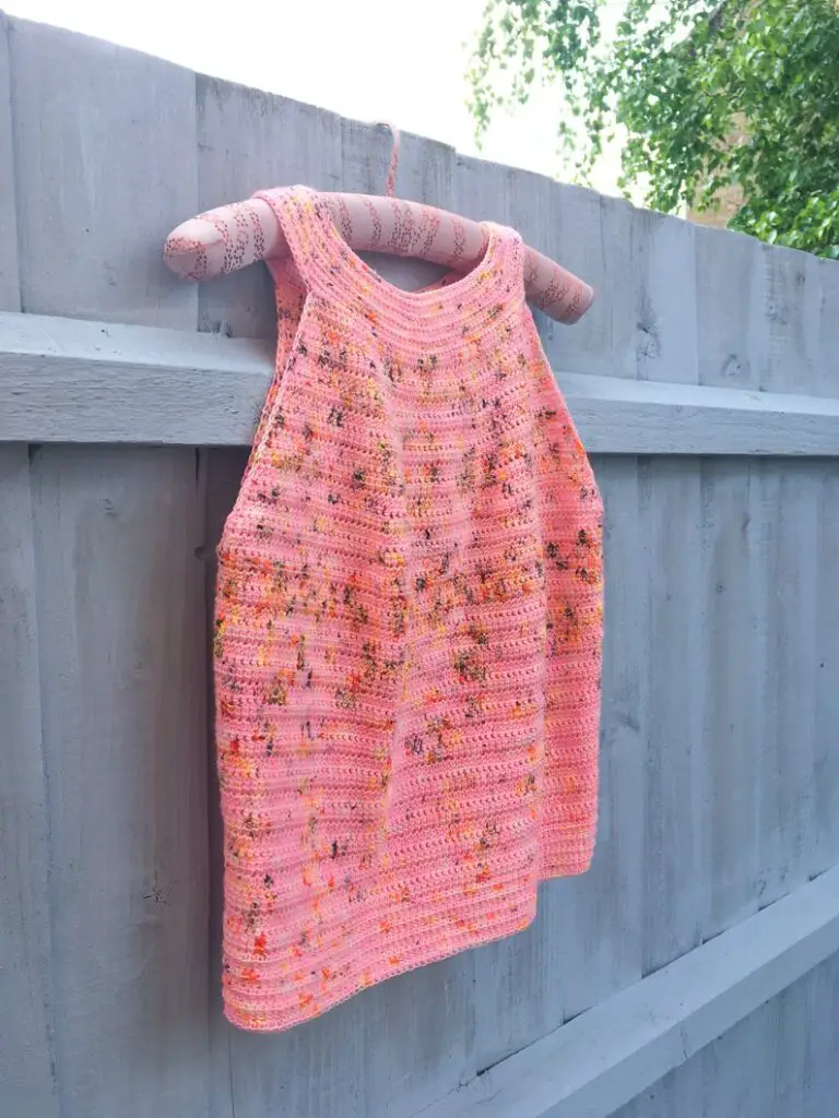 A crochet halter top hanging on a fence.  The ladies crochet top pattern is designed by Dora Does.