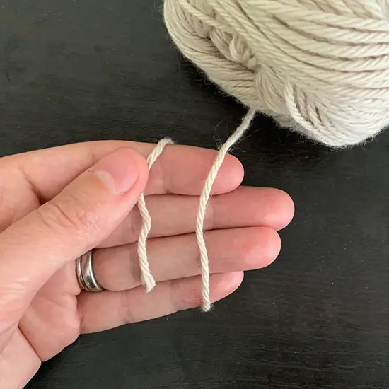 A hand with yarn wrapped around it.