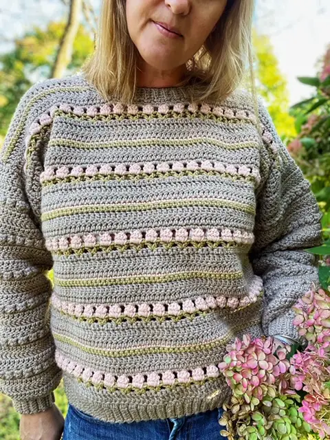 CoyCrochet models the Roses on Repeat Sweater, a size inclusive crochet sweater pattern.