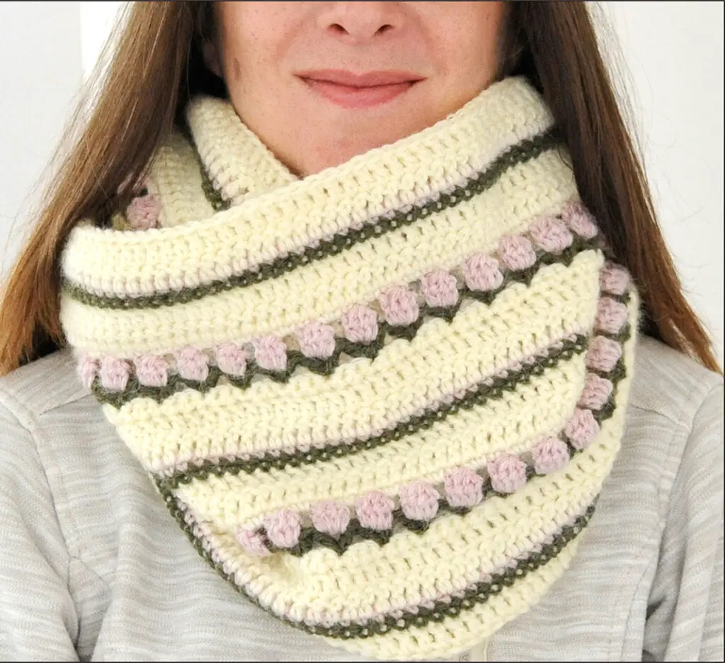 A close-up of the Roses on Repeat infinity scarf. The crochet infinity scarf has two rows of tulip stitch and three rows of matching stripes.