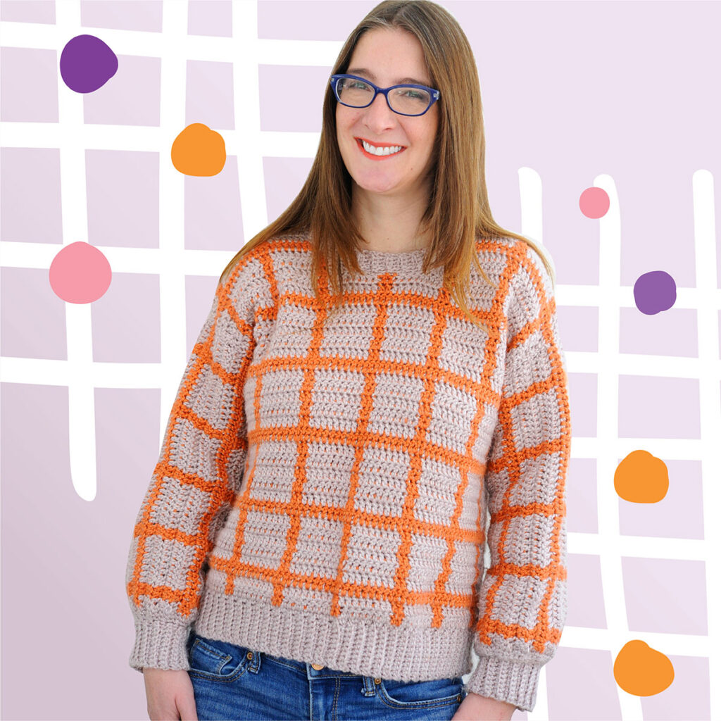 A woman wearing the Fair and Square Sweater in the yarn color combination lilac and orange.