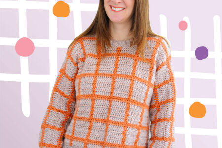 A woman wearing the Fair and Square Sweater in the yarn color combination lilac and orange.