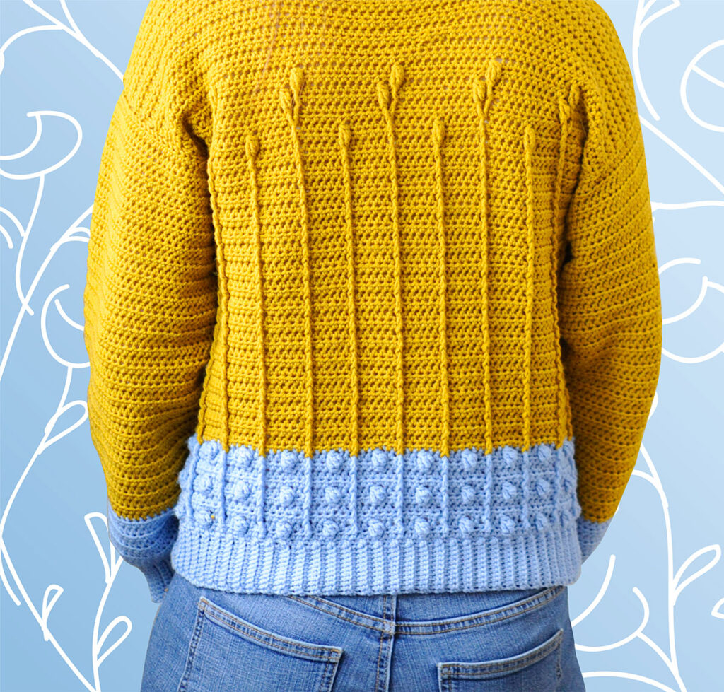 The back of the Best Buds Sweater pattern which is a modern indie crochet sweater pattern featuring a floral pattern in gold made with cable stitches, front post treble.
