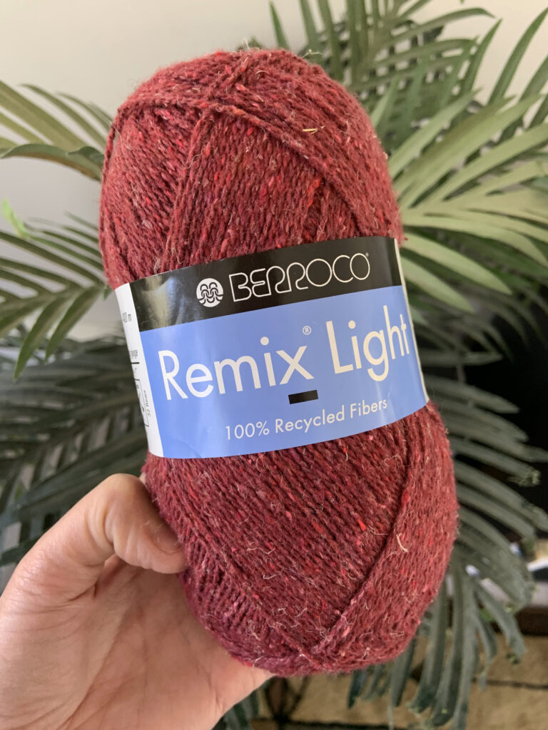 A woman holding a skein of Berroco Remix Light, a sustainable and recycled yarn.