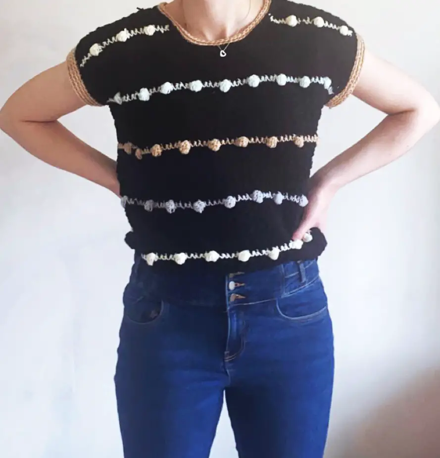 A black Lean Into Bobbles crochet t shirt with multicolored neutral bobbles being worn by a woman.