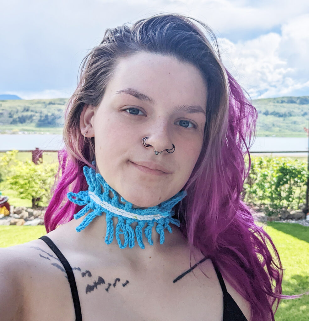 A woman with purple hair wearing a a crochet necklace.