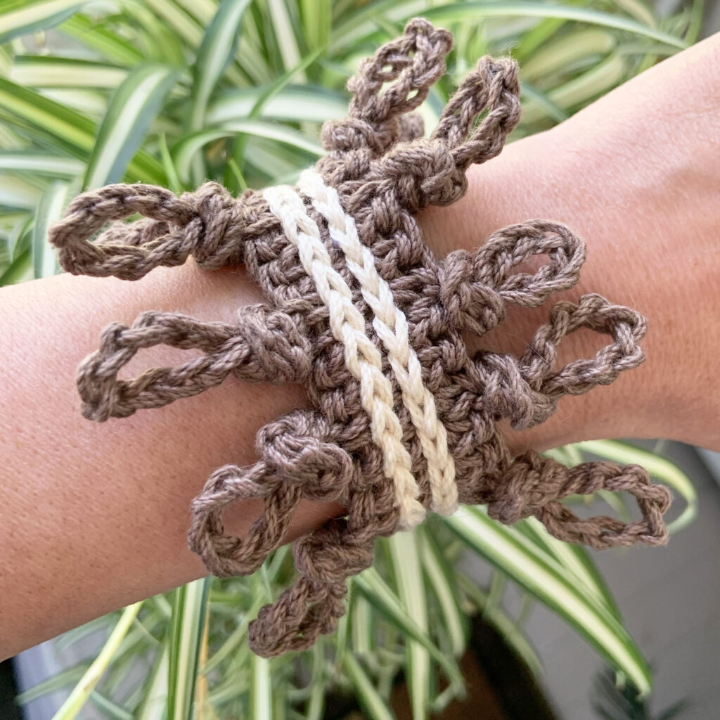 The wild knots free crochet bracelet pattern is a statement bracelet with featuring a while knotted border.