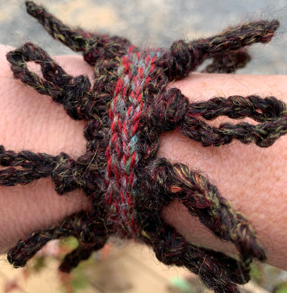 A Wild Knots Jewelry pattern made with handspun brown and red yarn.