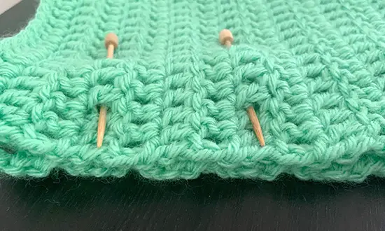 Two pieces of crochet ready for joining. Clover crochet pins hold the two pieces together one on top of each other.