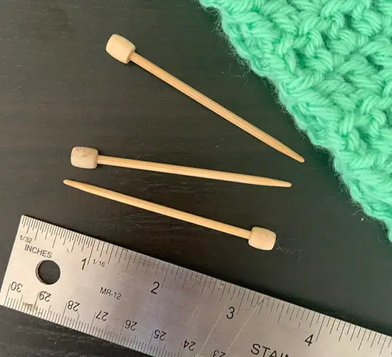 Three crochet pins next to a ruler.  You can see that the pins are 2.75" long.