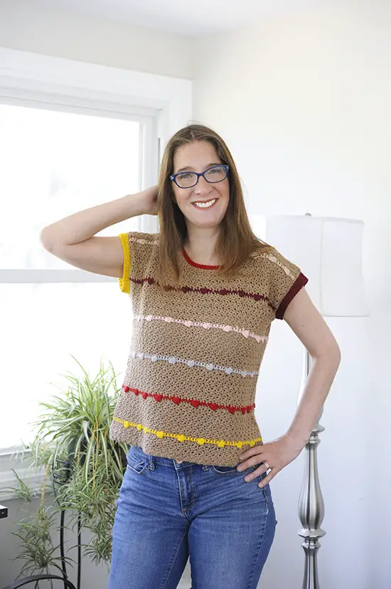 A woman wearing a crochet top with bobbles.  The top is stitched with a mattress stitch on the sides and a single crochet seam at the shoulder.