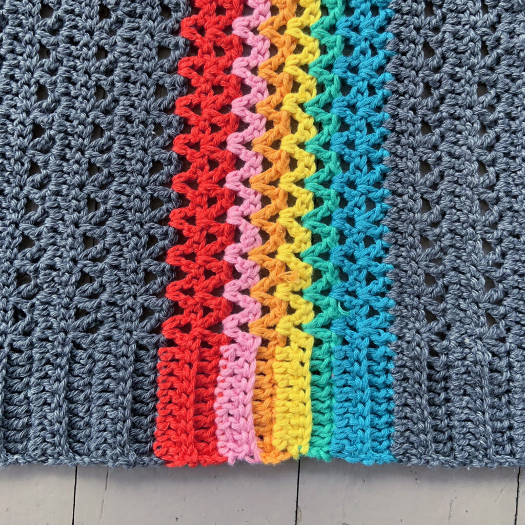 Close-up of Rainbow In My Pocket crochet cardigan.  Picture shows the rainbow section of the cardigan including the stitched in one piece ribbing.