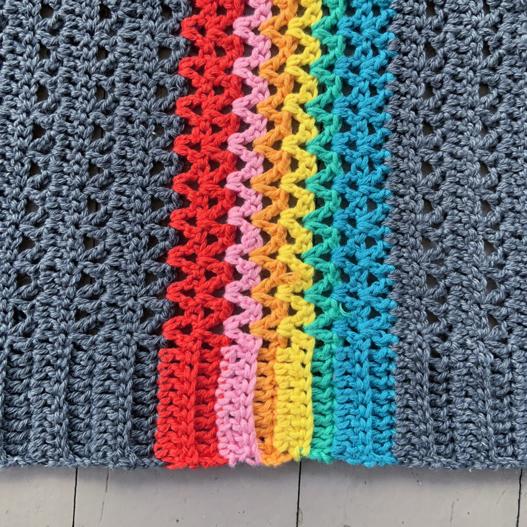 Close-up of Rainbow In My Pocket crochet cardigan. Picture shows the rainbow section of the cardigan including the stitched in one piece ribbing.